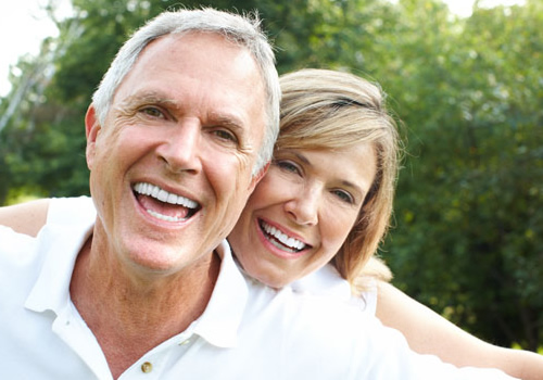 Imagem ilustrando um homem e uma mulher sorrindo com implante dental
